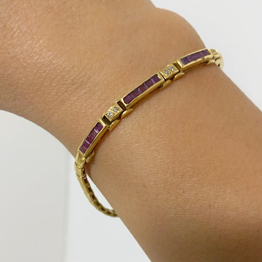 Pulsera semi rígida de oro de 18kt con 20 rubíes talla princesa y 6 diamantes talla brillante de 0.01ct cada uno. Esta preciosa pulsera vintage tiene un cierre cajón y doble cierre de seguridad. Pesa 12,33g con las piedras incluídas y mide 19cm. Compra joyas al mejor precio en Barcelona, compro oro barcelona