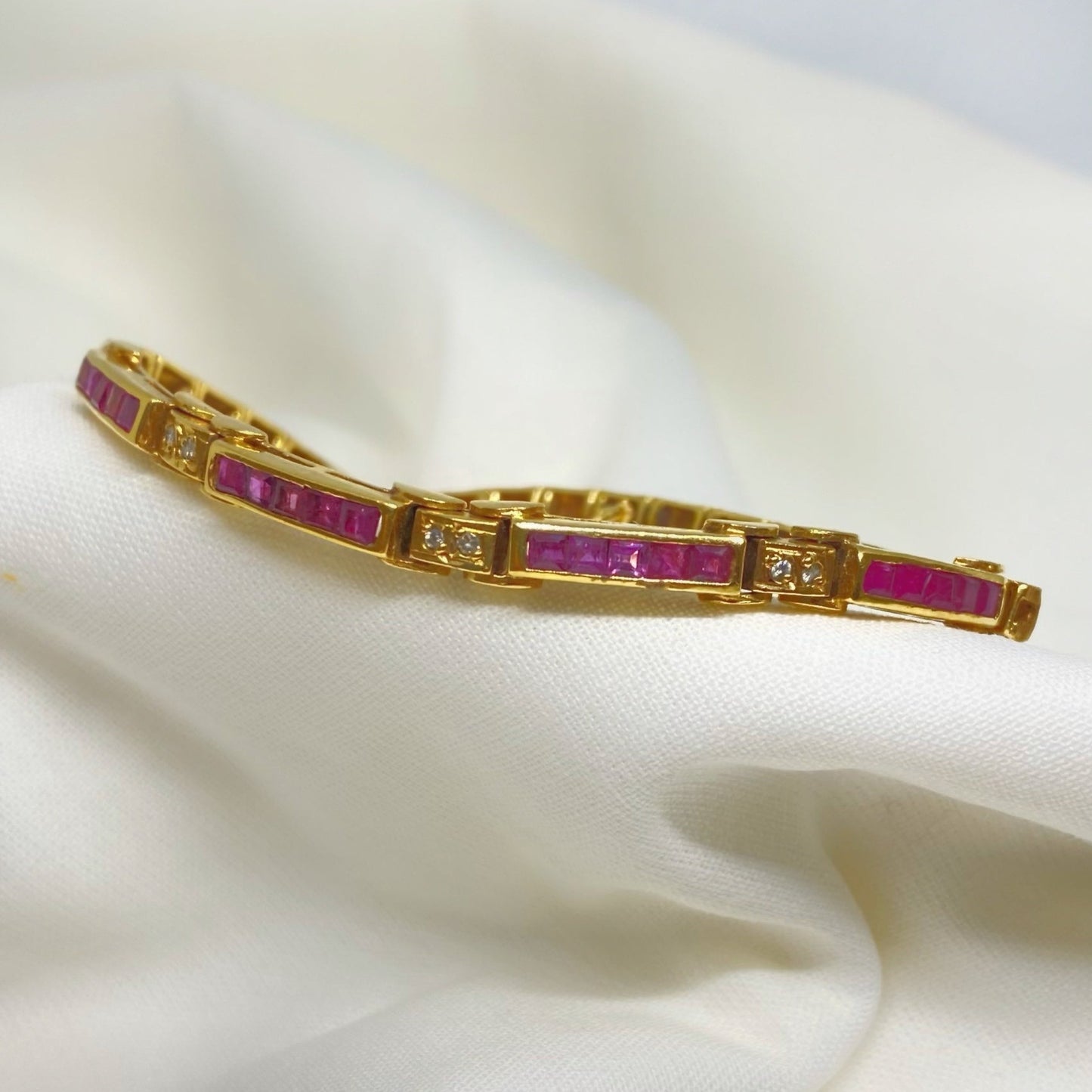 Pulsera semi rígida de oro de 18kt con 20 rubíes talla princesa y 6 diamantes talla brillante de 0.01ct cada uno. Esta preciosa pulsera vintage tiene un cierre cajón y doble cierre de seguridad. Pesa 12,33g con las piedras incluídas y mide 19cm. Compra joyas al mejor precio en Barcelona, compro oro barcelona