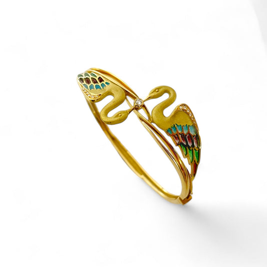 Espectacular pulsera de oro amarillo de 18kt tipo esclava con 2 cisnes que sujetan un diamante talla brillante. Esta esclava está inspirada en las joyas del artista Lluis Masriera, que revolucionó el sector de la joyería Art Noveau en Europa con sus piezas con motivos de la naturaleza , fantasía y color. Dispone de cierre tipo cajón y cierre de seguridad. Joyas antiguas y vintage en Barcelona, compro oro y joyas al mejor precio.