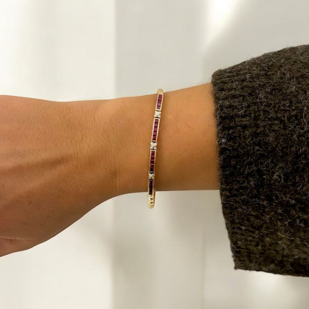Pulsera semirígida de oro amarillo de 18kt con 20 rubíes talla princesa y 15 diamantes talla brillante. Esta preciosa pulsera dispone de cierre cajón y doble cierre de seguridad. Pesa 10,51g y mide 19,8cm. Joyas de segunda mano en Barcelona, compro oro y joyas al mejor precio. Joyería Compro Oro Barcelona, el mejor precio por tu oro y por joyas de segunda mano.