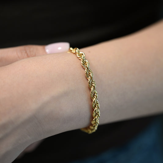 Comprar Pulsera de cordón de oro amarillo de 18kt de 19,5 cm de largo caracterizada por su diseño trenzado en espiral y un cierre de mosquetón. Pulseras de oro 18kt al mejor precio en Barcelona.