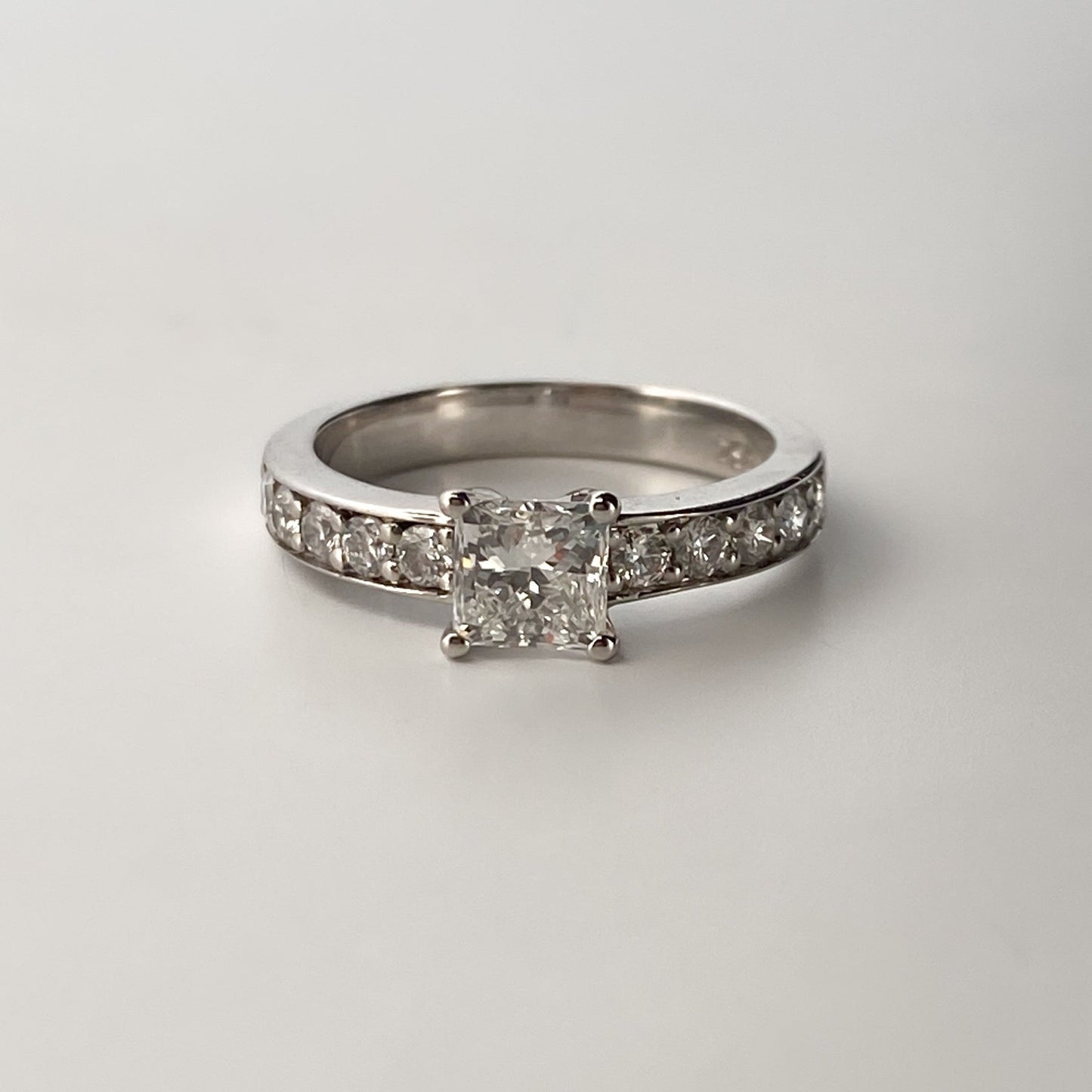 Solitario talla princesa realizado en oro blanco de 18kt y carril de 5 diamantes en cada brazo. Anillos de compromiso al mejor precio. Envío gratis. Joyería Ian'Or Barcelona