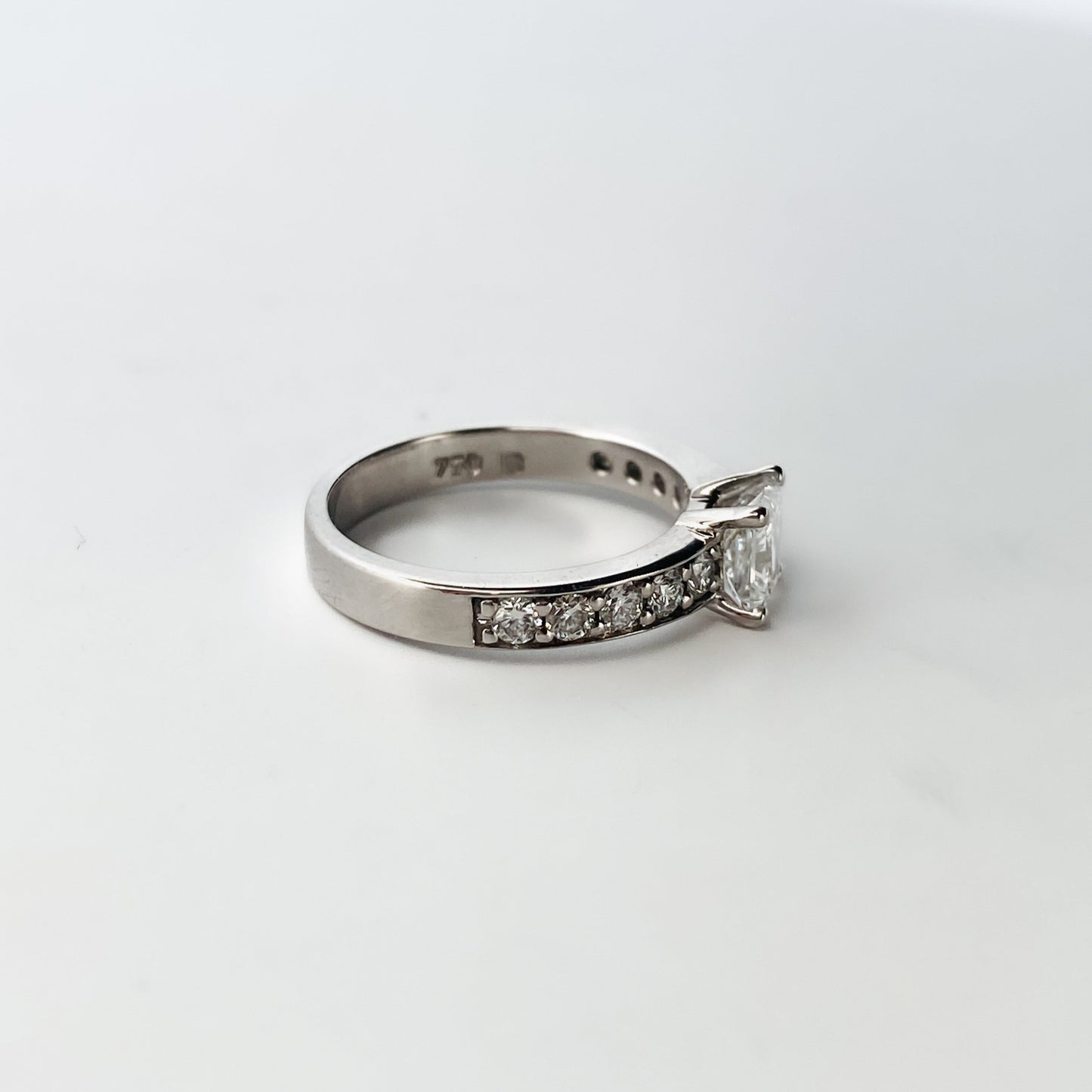 Solitario talla princesa realizado en oro blanco de 18kt y carril de 5 diamantes en cada brazo. Anillos de compromiso al mejor precio. Envío gratis. Joyería Ian'Or Barcelona