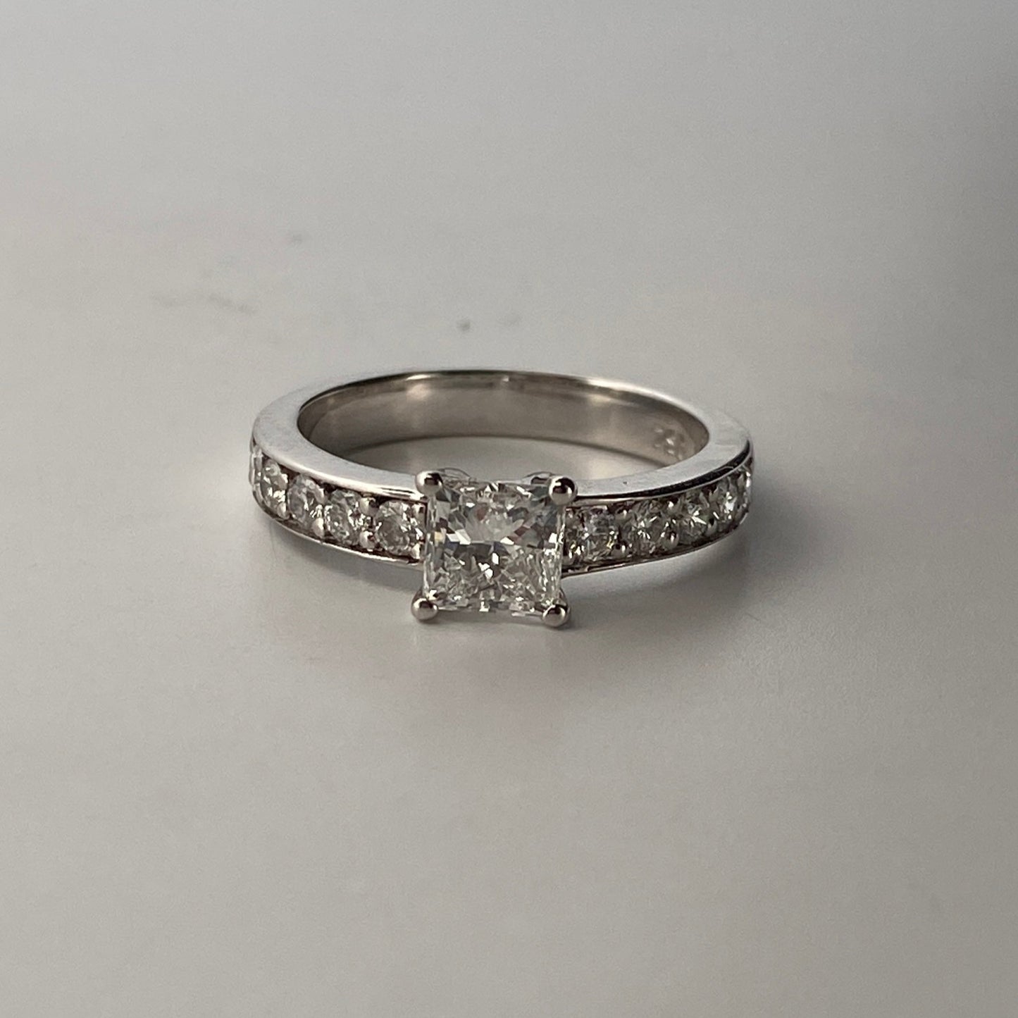 Solitario talla princesa realizado en oro blanco de 18kt y carril de 5 diamantes en cada brazo. Anillos de compromiso al mejor precio. Envío gratis. Joyería Ian'Or Barcelona