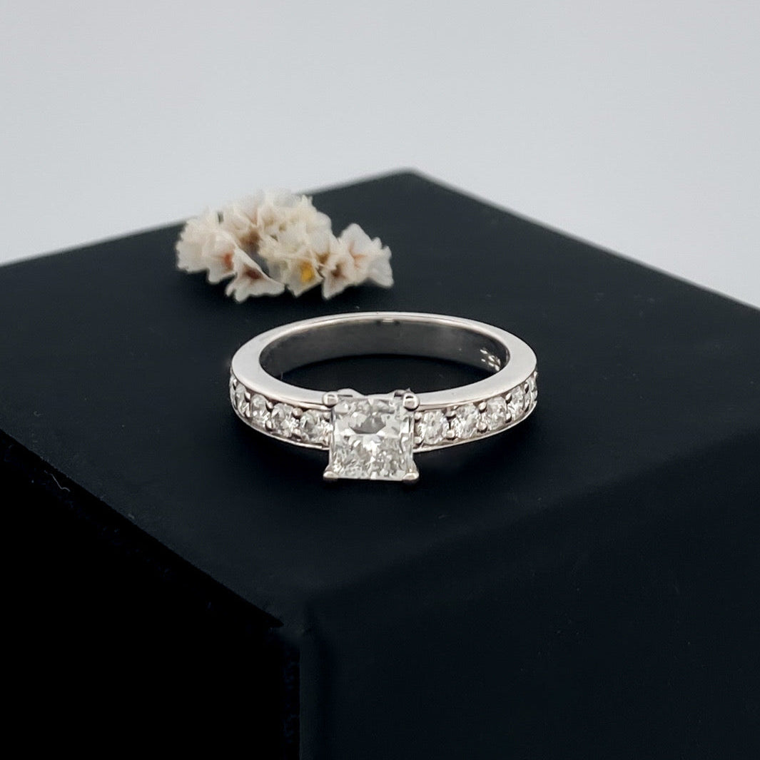 Solitario talla princesa realizado en oro blanco de 18kt y carril de 5 diamantes en cada brazo. Anillos de compromiso al mejor precio. Envío gratis. Joyería Ian'Or Barcelona