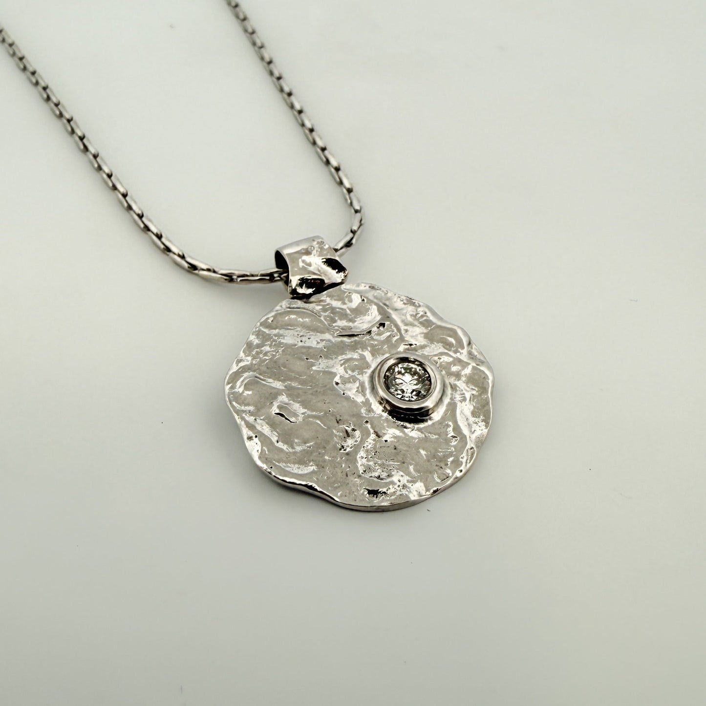 Comprar colgante en forma redondeada con textura en oro blanco de 18kt y diamante con engaste chatón. Joyería Ian'Or. Joyas restauradas. Envío gratis.