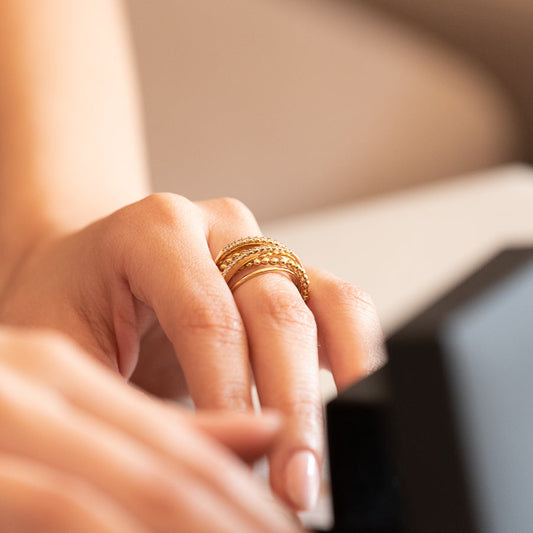 Anillo realizado en oro amarillo de 18kt con seis bandas unidas entre si, dos de ellas lisas dos con motivos de bolitas i dos medias alianzas con diamantes talla brillante