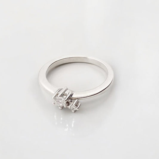 Anillo en oro blanco de 18kt de la firma Tous con un diamante central engastado en 6 grapas y un diamante más pequeño colgante de una de las grapas.