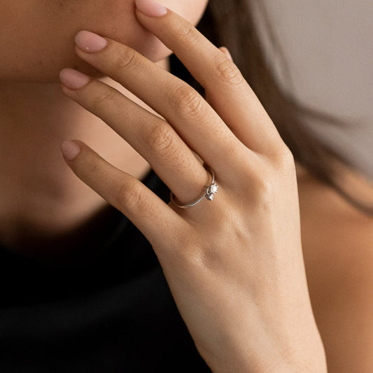 Anillo en oro blanco de 18kt de la firma Tous con un diamante central engastado en 6 grapas y un diamante más pequeño colgante de una de las grapas.