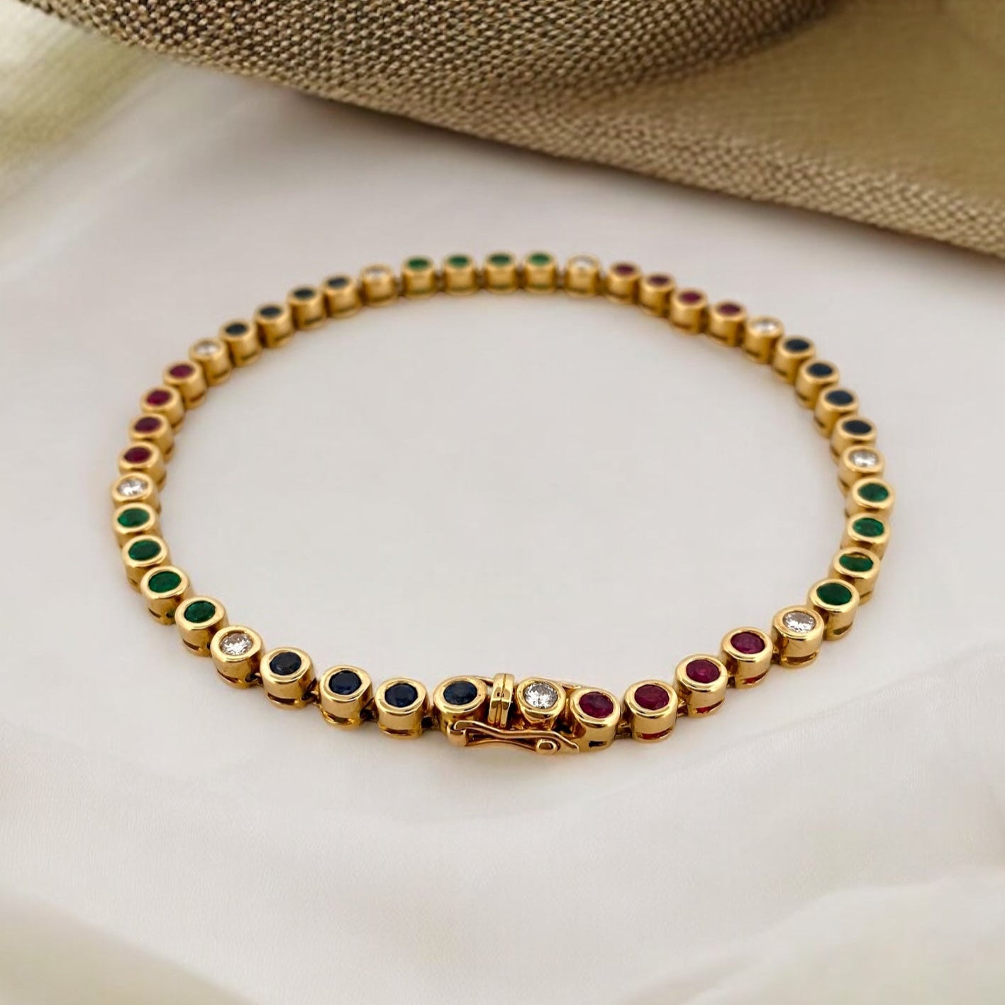 Pulsera semirígida de oro de 18kt con 3 rubíes, 3 esmeraldas y 30 zafiros azules talla princesa. Joyería Ian'Or. Joyas segunda vida. Envío GRATIS.