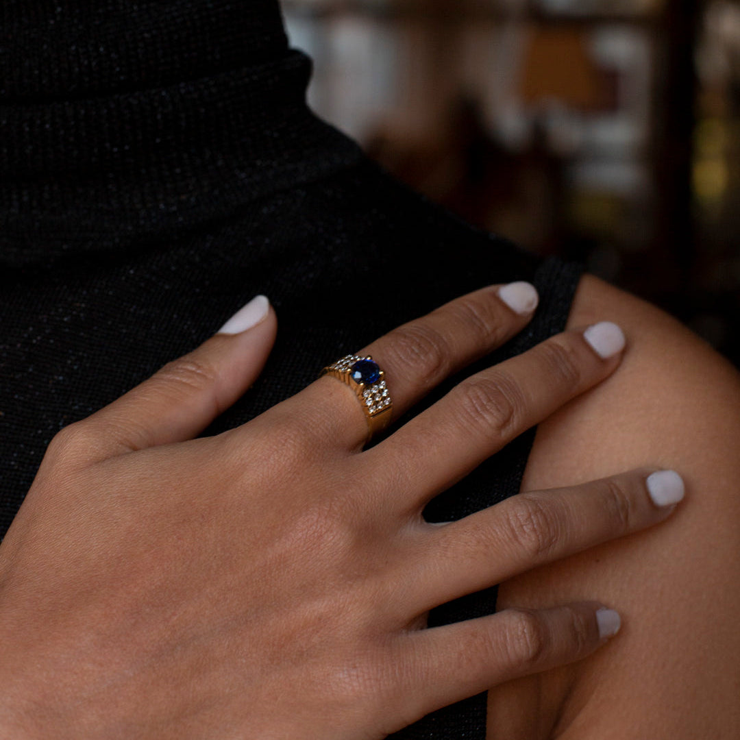 Comprar anillo realizado en oro amarillo de 18kt con un zafiro central engastado en 4 grapas y 9 diamantes cada lado. Joyas de segunda mano Barcelona. Envío gratis.