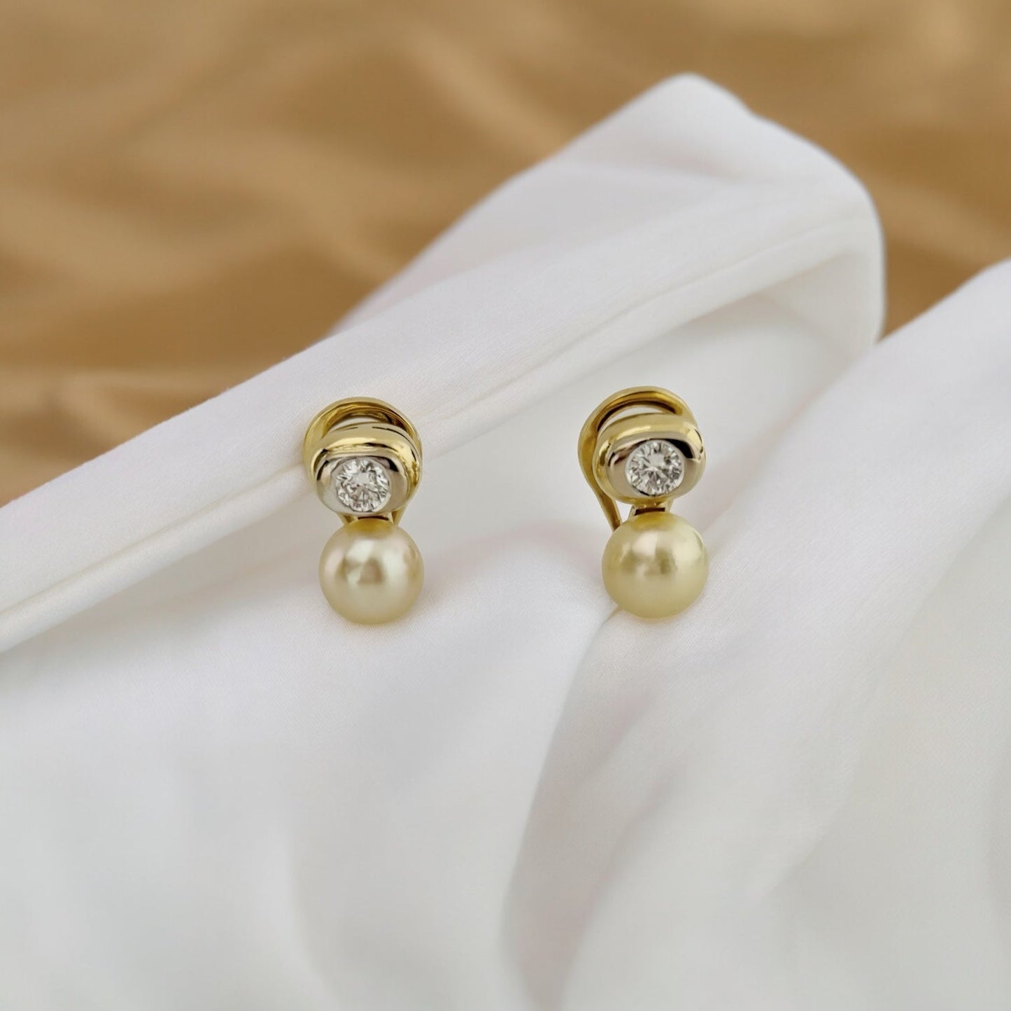 Pendientes tu y yo de oro amarillo de 18kt de la firma Vasari con 2 diamantes de __ cada uno y perla cultivada de 6,30mm cada una. Estos preciosos pendientes disponen de cierre tipo Omega Joyería Barcelona, segunda mano, restauración y creación de joyas, compro oro Barcelona. Joyas Vasari y joyería de lujo.