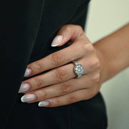 Anillo de oro blanco de 18kt con Rosetón de diamante central de 0,45ct y orla de 10 diamantes de 0,10ct y engaste lateral de 18 brillantes de 0,01ct cada uno. 