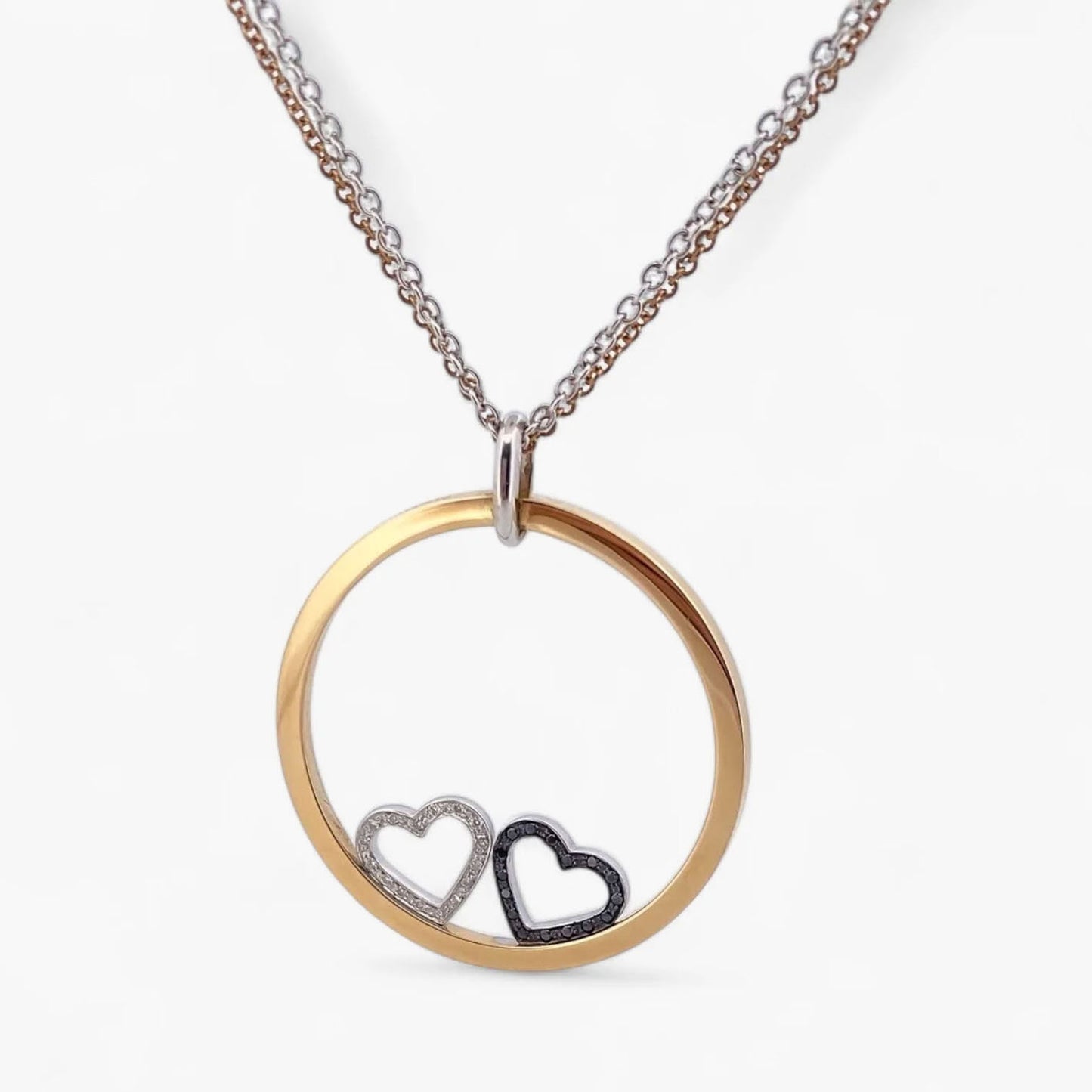 Collar de la firma Pesavento en oro blanco y amarillo de 18kt con circunferencia y dos corazones en su interior. Collar con diamantes negros y blancos.