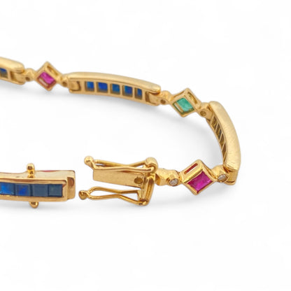 Pulsera semirígida de oro de 18kt con 3 rubíes, 3 esmeraldas y 30 zafiros azules talla princesa. Esta preciosa pulsera vintage dispone de cierre cajón y doble cierre de seguridad. Pesa 13,89g y mide 19cm.