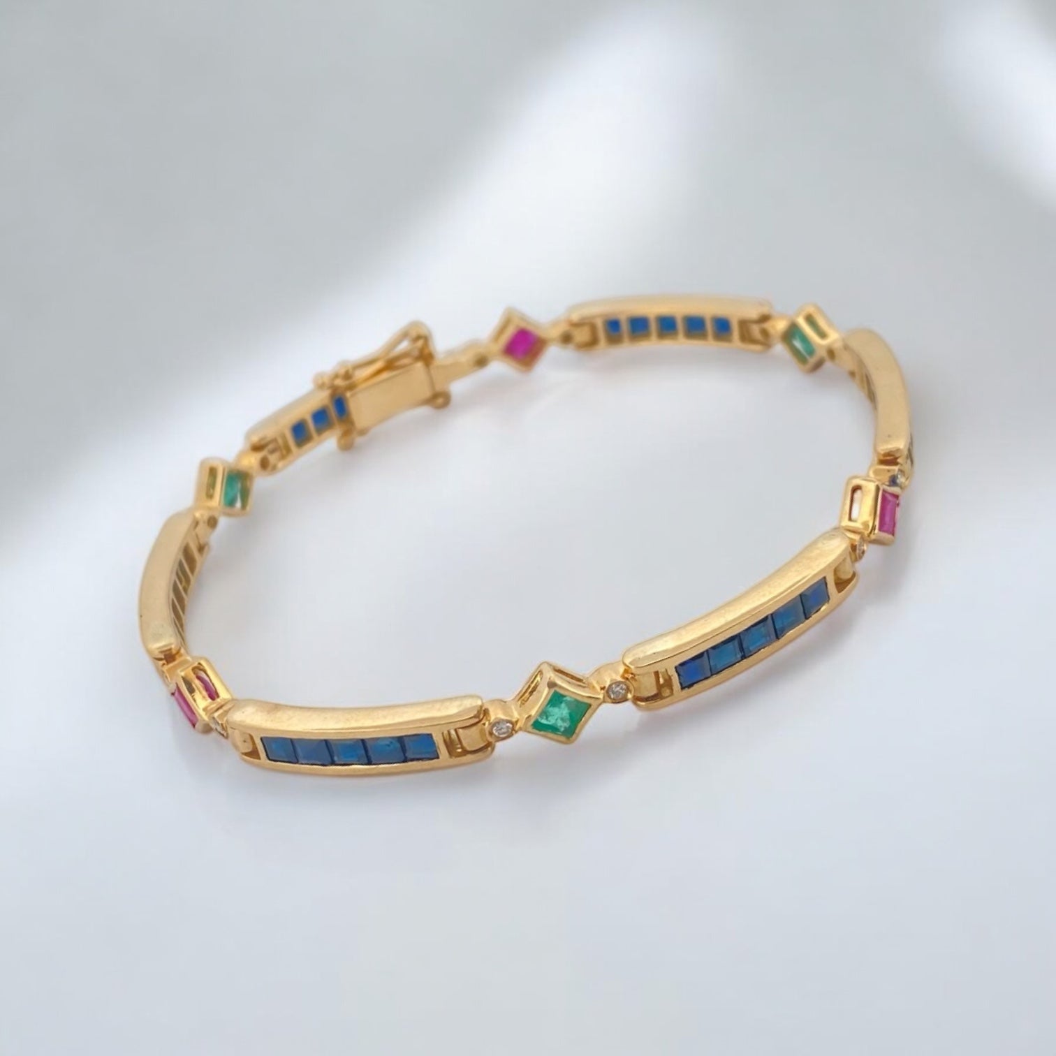 Pulsera semirígida de oro de 18kt con 3 rubíes, 3 esmeraldas y 30 zafiros azules talla princesa. Esta preciosa pulsera vintage dispone de cierre cajón y doble cierre de seguridad. Pesa 13,89g y mide 19cm.