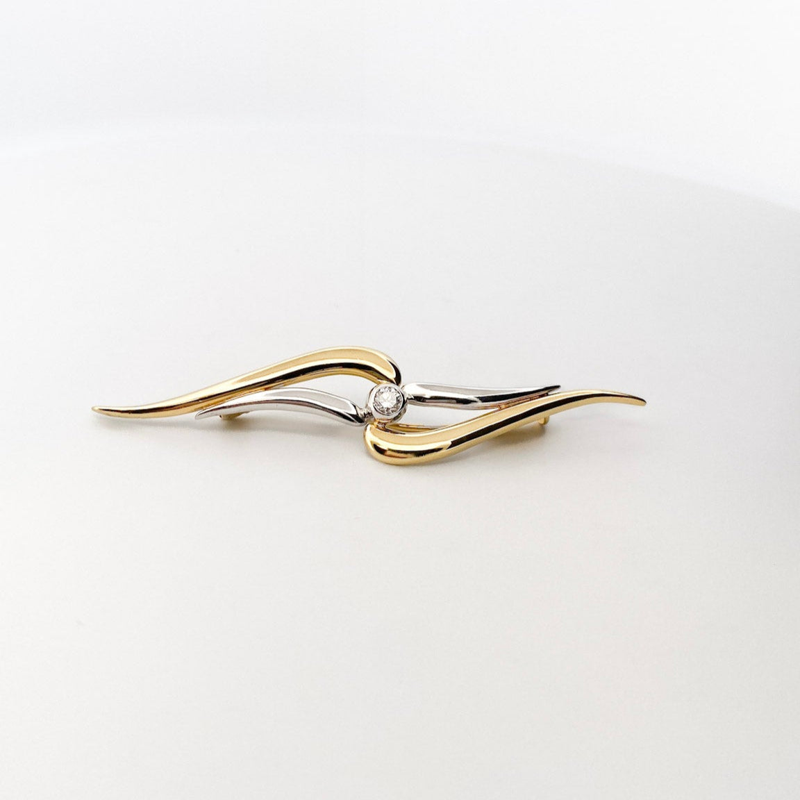 Broche realizado en oro amarillo y oro blanco de 18kt con un diamante talla brillante en la parte central. Broches baratos. Joyería Ian'Or. Joyas baratas en Bcn