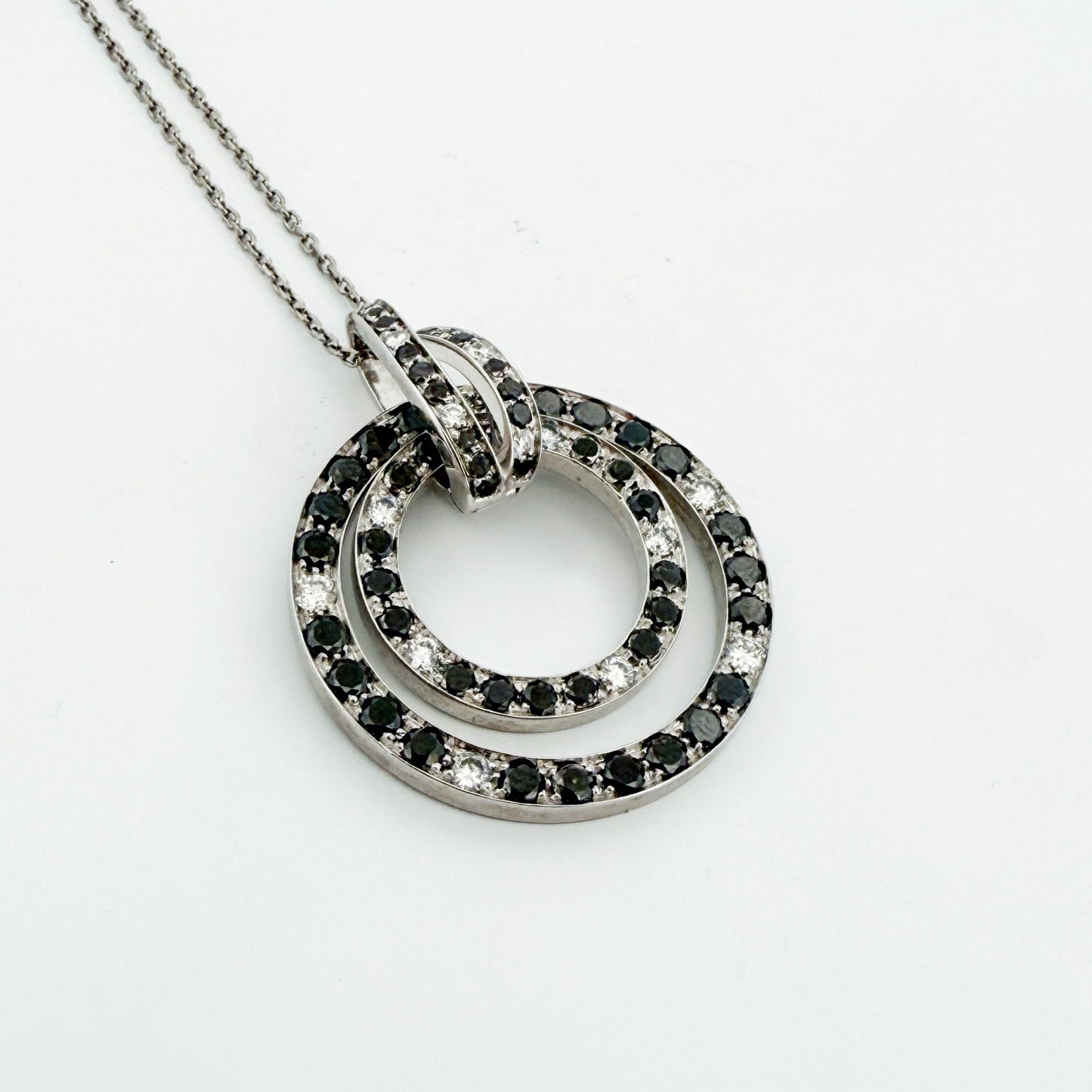 Comprar colgante en oro blanco de 18kt en forma de círculos con diamantes negros y blancos. Joyas segunda mano. Joyería Ian'Or.