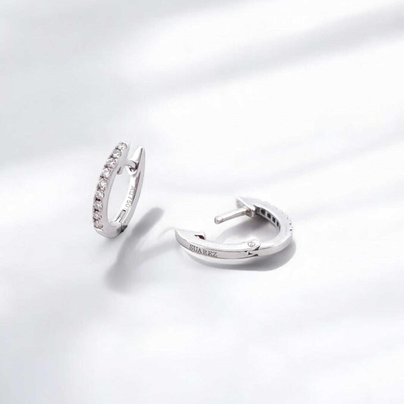 Comprar pendientes Suarez de oro blanco de 18kt en forma de aro pequeño y 9 diamantes talla brillante en cada pendiente. Cierre catalán. Joyería Ian'Or.