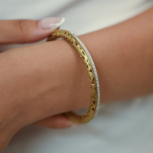 Comprar pulsera esclava de oro amarillo de 18kt en acabado mate y diseño de corazones con carril de oro blanco y 33 diamantes talla brillante. Joyería Ian'Or.