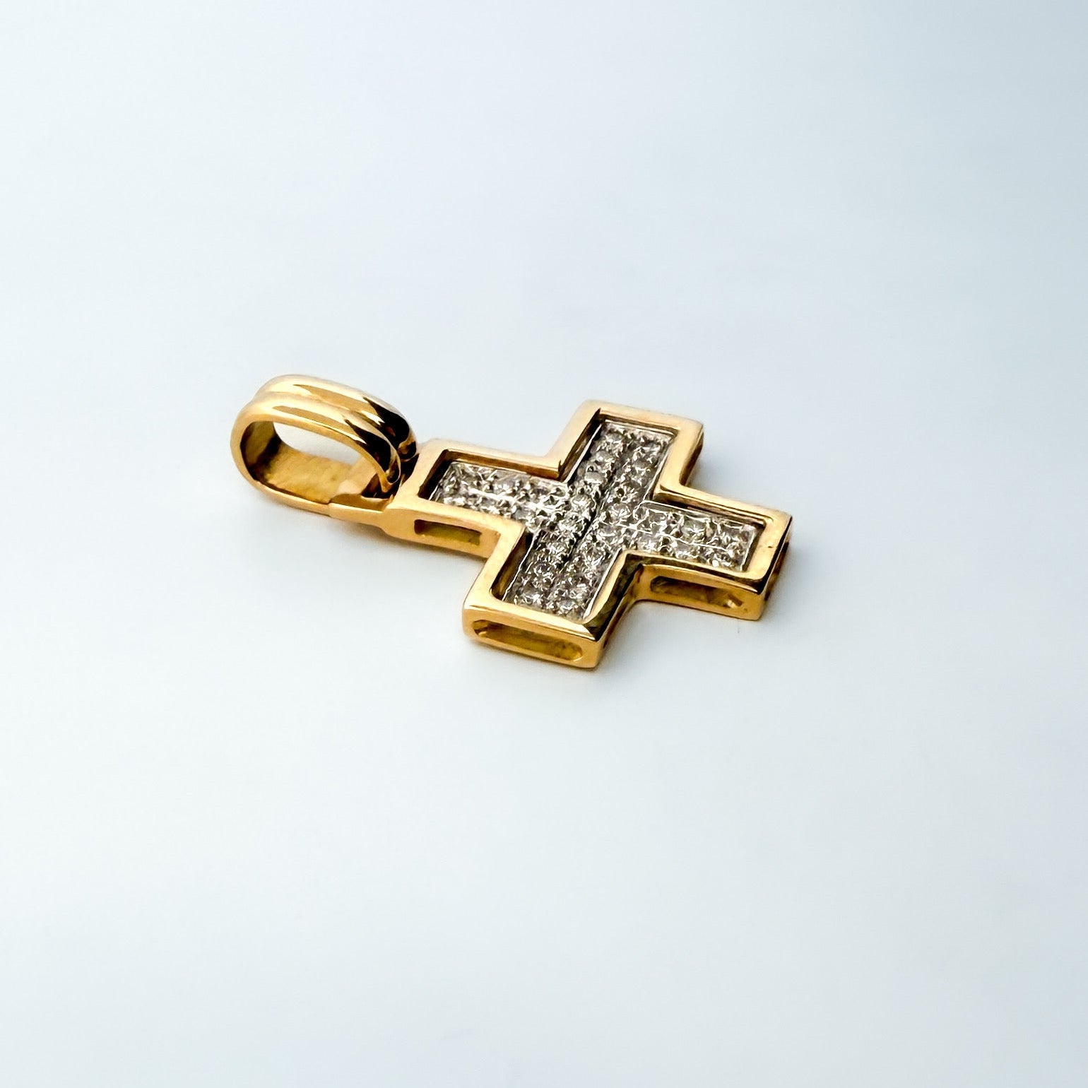 Colgante bicolor en forma de cruz cuadrada realizada en oro amarillo de 18kt con engaste en oro blanco de 28 diamantes talla brillante.