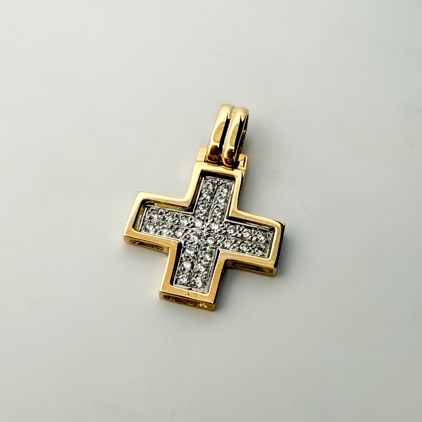 Colgante&nbsp; bicolor en forma de cruz cuadrada&nbsp; realizada en oro amarillo de 18kt con engaste en oro blanco de 28 diamantes talla brillante.