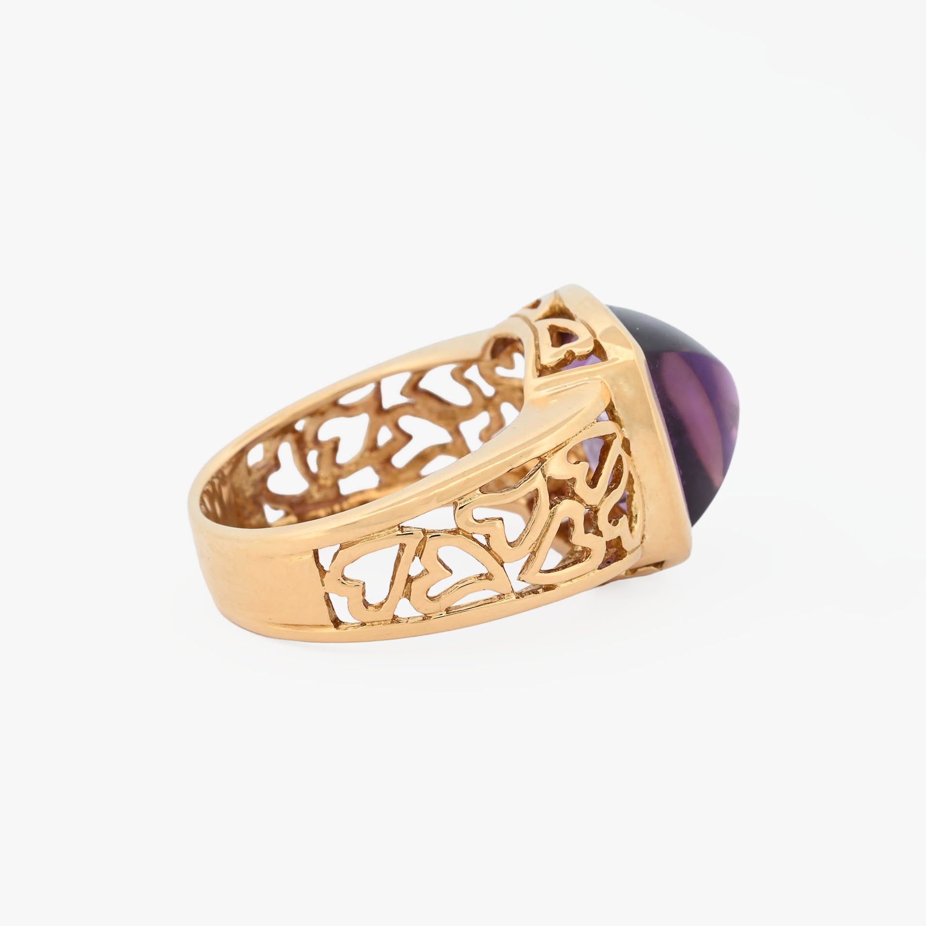 Comprar anillo ancho de oro amarillo de 18kt y amatista cabujon en forma de piramide, montada en un aro semicalado con formas de corazon. 