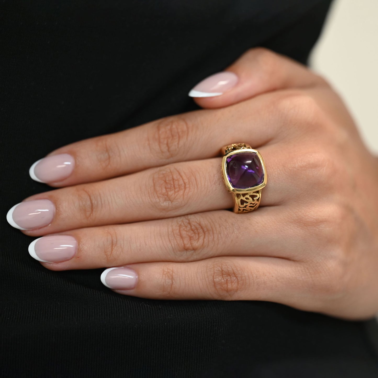 Comprar anillo ancho de oro amarillo de 18kt y amatista cabujon en forma de piramide, montada en un aro semicalado con formas de corazon. 