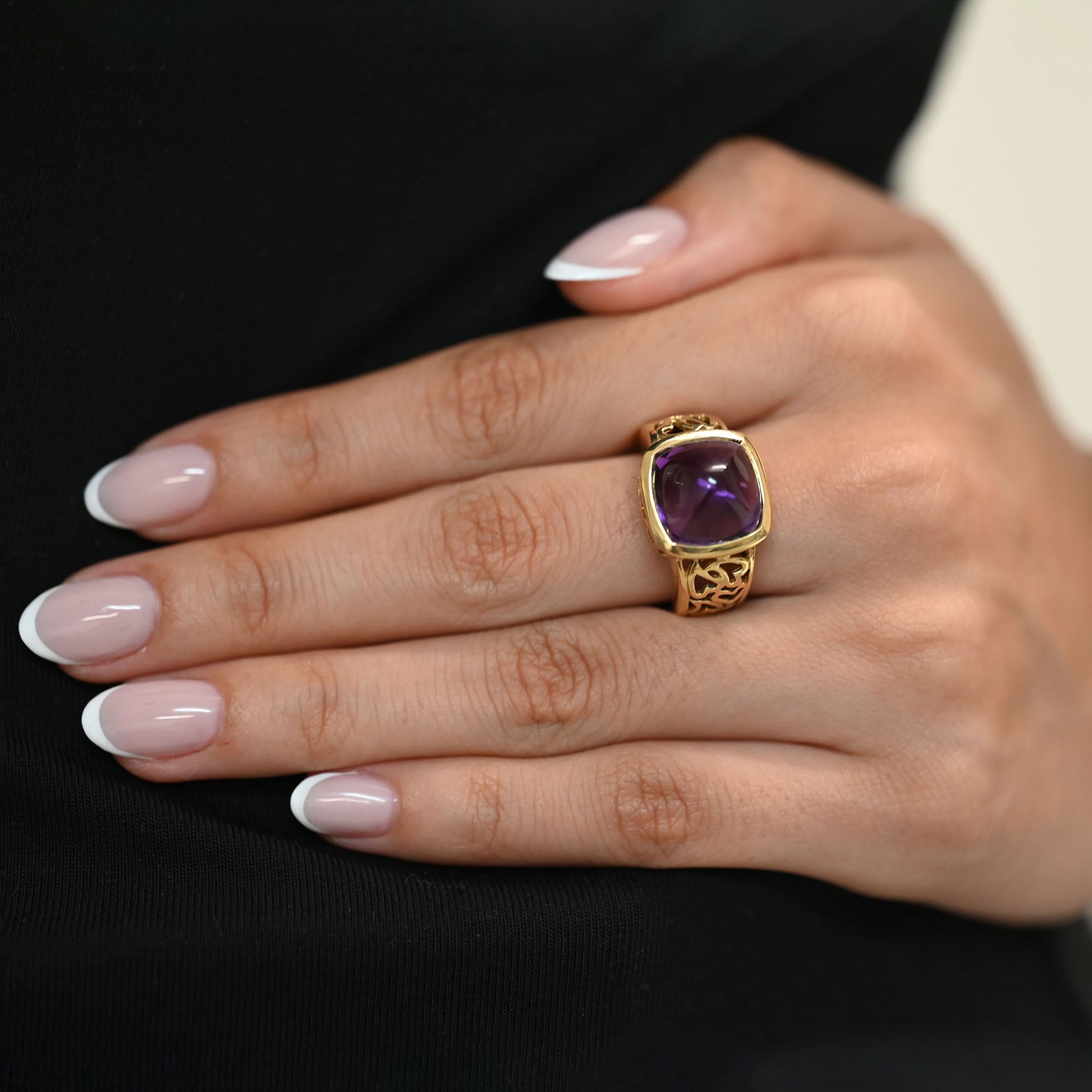 Comprar anillo ancho de oro amarillo de 18kt y amatista cabujon en forma de piramide, montada en un aro semicalado con formas de corazon. 