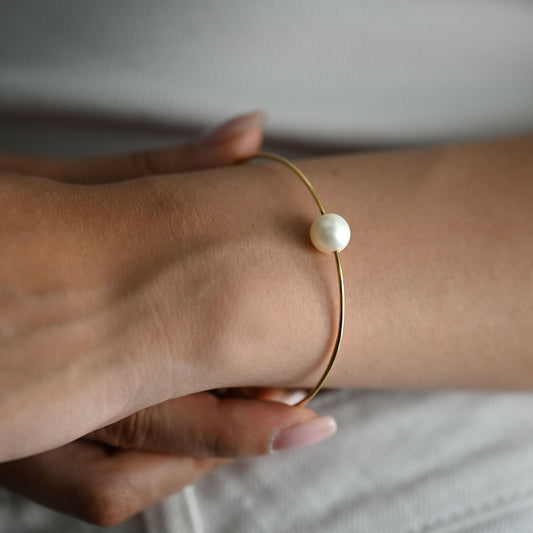 Comprar pulsera tipo esclava de oro amarillo de 18k con una perla cultivada de 9.08mm, una pieza minimalista y elegante que habla por si sola. Envío gratuito