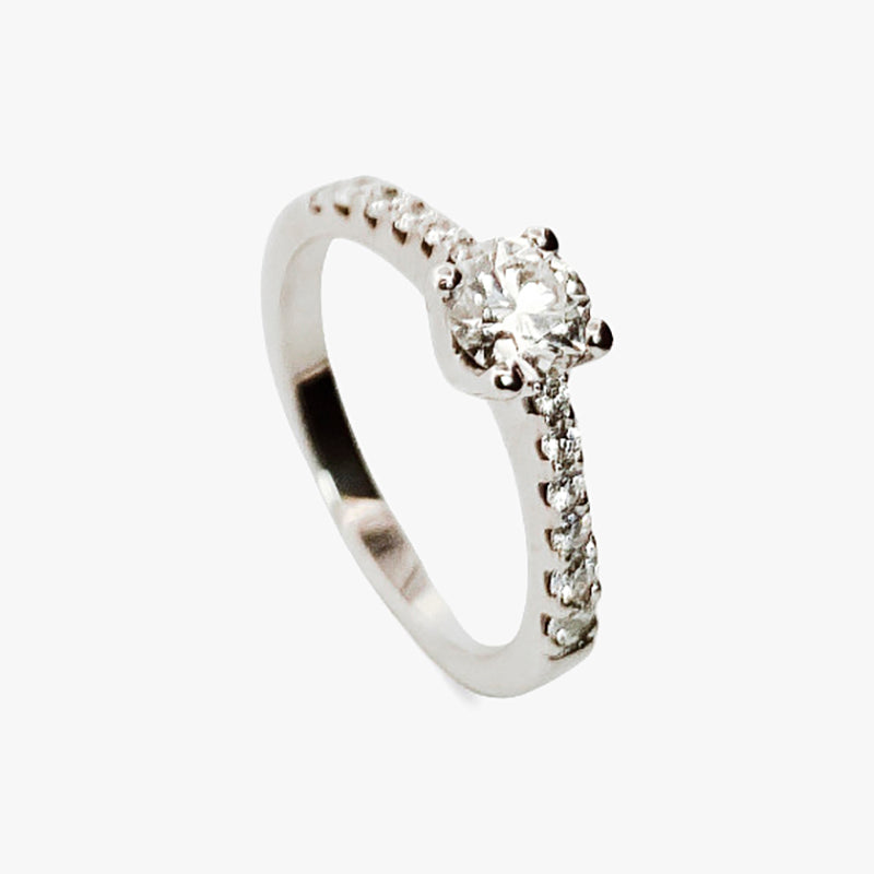 Comprar sortija en oro blanco de 18kt con rosetón de diamantes alrededor de un diamante central y carril de diamantes escalonados en brazos. Envio gratis