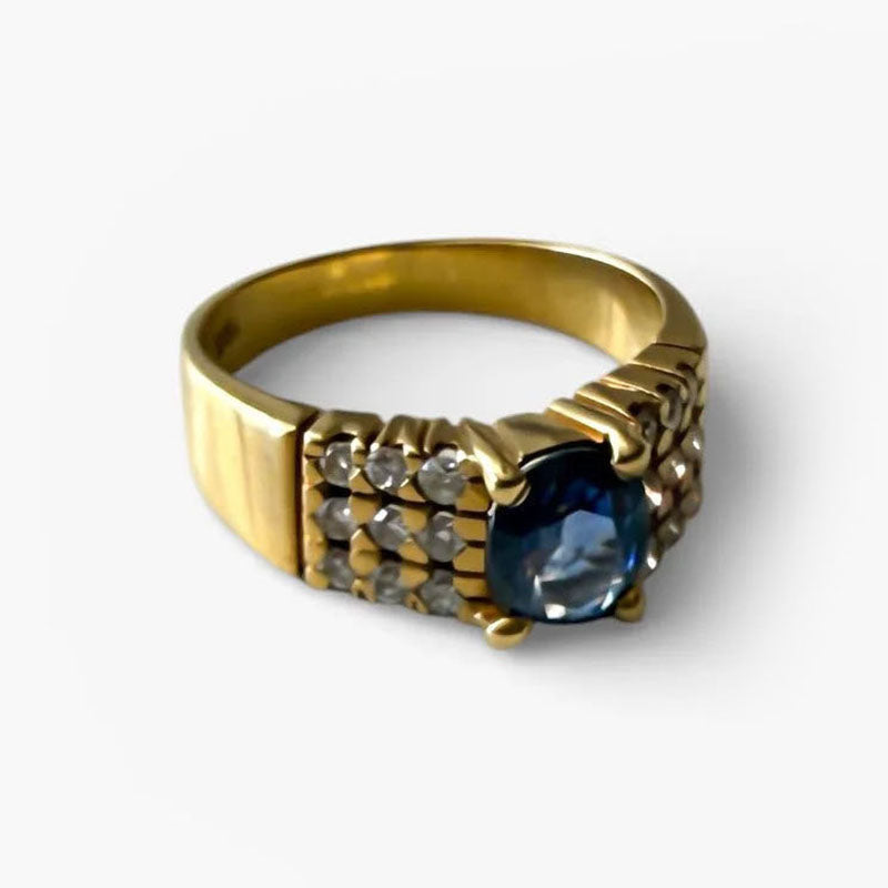 Comprar anillo realizado en oro amarillo de 18kt con un zafiro central engastado en 4 grapas y 9 diamantes cada lado. Joyas de segunda mano Barcelona. Envío gratis.