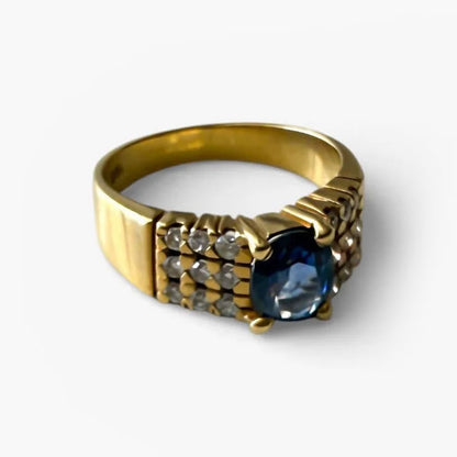 Comprar anillo realizado en oro amarillo de 18kt con un zafiro central engastado en 4 grapas y 9 diamantes cada lado. Joyas de segunda mano Barcelona. Envío gratis.