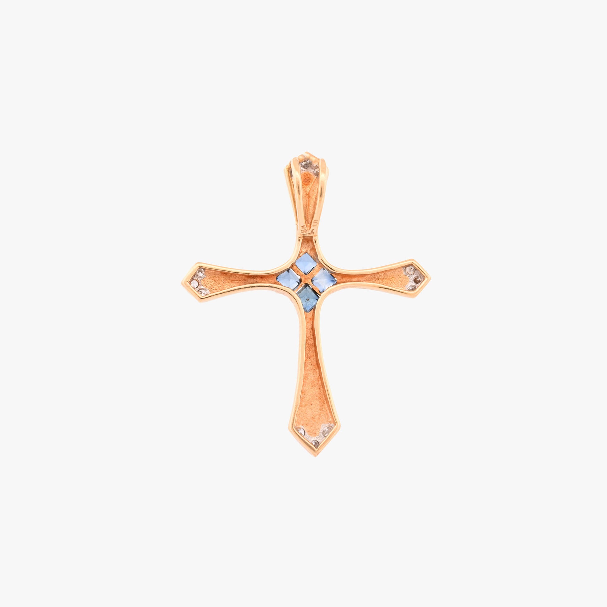Colgante en forma de cruz latina de oro amarillo de 18kt y combinada con zafiros y brillantes. La cruz destaca por su diseño de líneas curvas estilizadas, un marcado juego de texturas y una cuidada selección de pedreria fina que combina zafiros centrales con pavé de diamantes en los extremos.